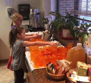 Two Adventure Bible Class students washing used pill bottles to prepare them for use in fishing kits. 